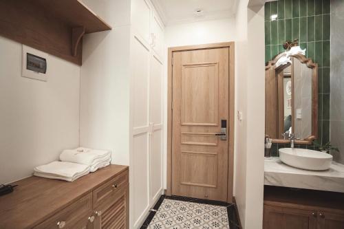 a bathroom with a wooden door and a sink at Samson Soleil Hotel in Sầm Sơn