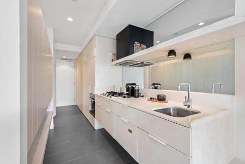 a kitchen with white cabinets and a sink at Chic City Escape with Pool, Gym & Parking in Melbourne