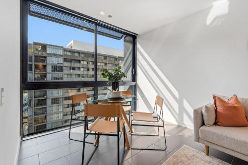 a balcony with a table and chairs and a couch at Chic City Escape with Pool, Gym & Parking in Melbourne