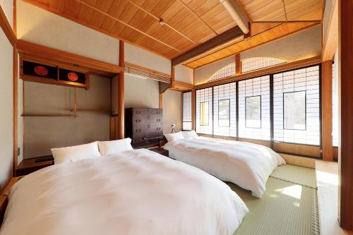 two beds in a room with two windows at YASUYA-yasuya- in Yasugi