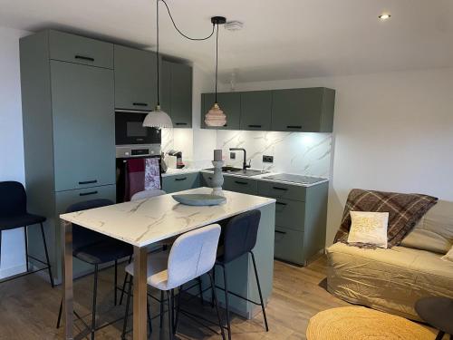 une cuisine avec des armoires vertes, une table et des chaises dans l'établissement Appartement cosy au Chinaillon, proche des pistes, animaux admis - FR-1-467-145, au Grand-Bornand