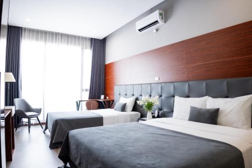 a hotel room with two beds and a chair at Mango Hotel - Ha Noi Railway station in Hanoi