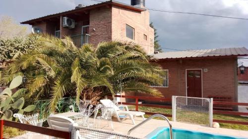 a house with a palm tree next to a swimming pool at Complejo "El Padrino" in Villa Carlos Paz