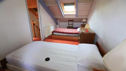 Cette petite chambre mansardée comprend un lit et un bureau. dans l'établissement Maison 3 chambres 6 lits 82 m2, à Saint-Quay-Portrieux
