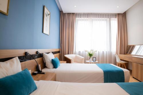 a hotel room with two beds and a window at Mango Hotel - Ha Noi Railway station in Hanoi