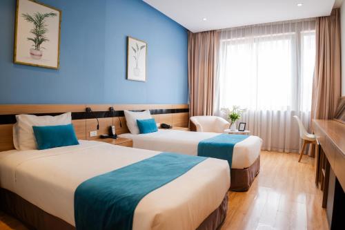 two beds in a hotel room with blue walls at Mango Hotel - Ha Noi Railway station in Hanoi
