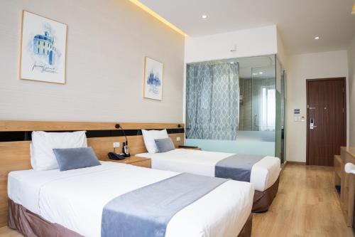 a hotel room with two beds and a bathroom at Mango Hotel - Ha Noi Railway station in Hanoi