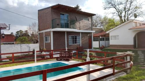 a house with a swimming pool in front of a house at Complejo "El Padrino" in Villa Carlos Paz