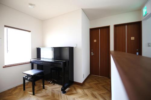 a living room with a piano and a window at Ayumi STAY 駐車1台のみ in Sapporo