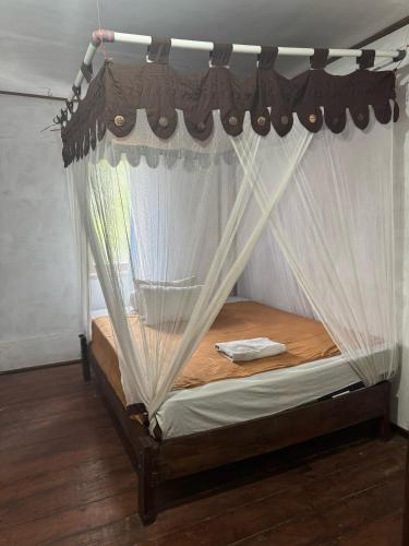 a bedroom with a canopy bed with white curtains at Santai Guesthouse Balangan in Uluwatu