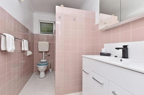 Baño de color rosa con aseo y lavamanos en Waterfront Reflections, en Corlette