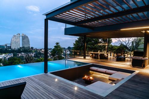 an outdoor patio with a fireplace and a swimming pool at Amulya Luxury Villa, Dago - 4BR Heated Infinity Pool in Bandung