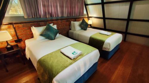 a hotel room with two beds and a lamp at The Bukit Resort Langkawi in Kampung Padang Masirat