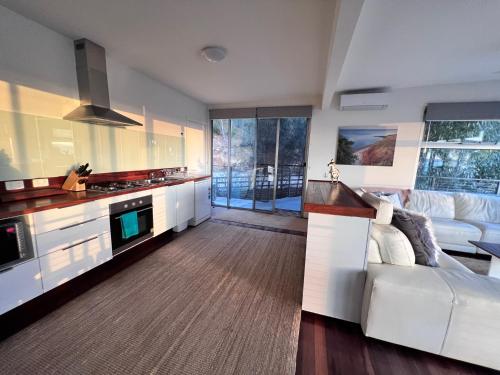 a living room with a white couch and a kitchen at Sunrise on Falie Seaview Eco Accommodation in American River