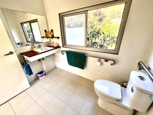 a bathroom with a toilet and a sink and a window at Sunrise on Falie Seaview Eco Accommodation in American River