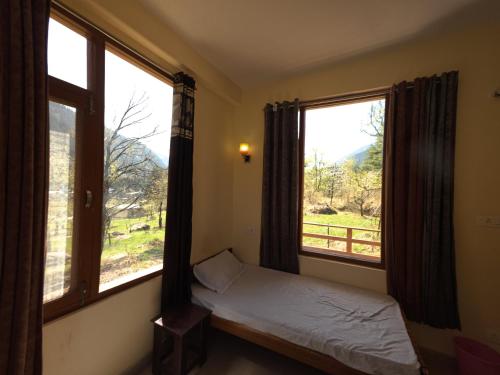1 dormitorio con 2 ventanas grandes y 1 cama en la parte delantera en By The Way, en Manali