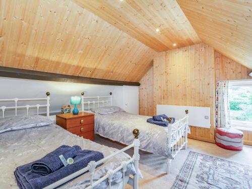a bedroom with two beds and a wooden ceiling at Duck Cottage in Bridlington