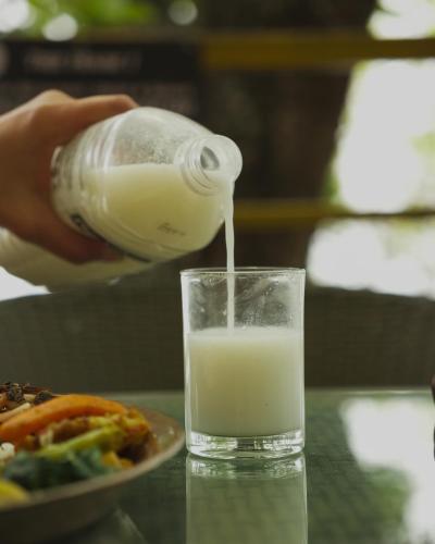 a bottle of milk is being poured into a glass at Naya Gaun Eco Resort in Pokhara