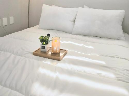 a candle on a tray on a white bed at feel at Home in Incheon