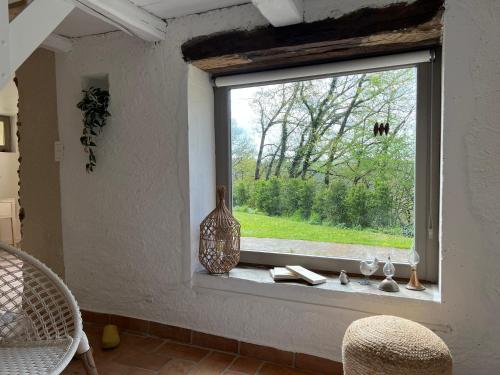 a window with a vase and books on a window sill at L écrin des bois in Sauveterre-de-Rouergue