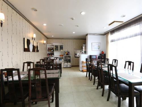 a dining room with tables and chairs and a kitchen at ゴールデンビーチホテル in Katakai