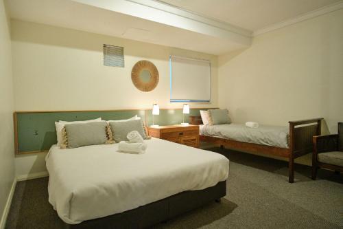 a hotel room with two beds and a chair at Oceanhaus - Margaret River in Margaret River Town