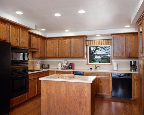 a kitchen with wooden cabinets and a black appliance at Lakefront near Seattle, Mt Rainier & Ocean Shores in Spanaway