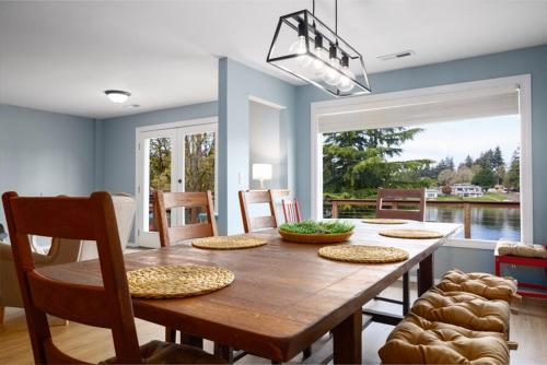 a dining room with a wooden table with chairs and a large window at Lakefront near Seattle, Mt Rainier & Ocean Shores in Spanaway