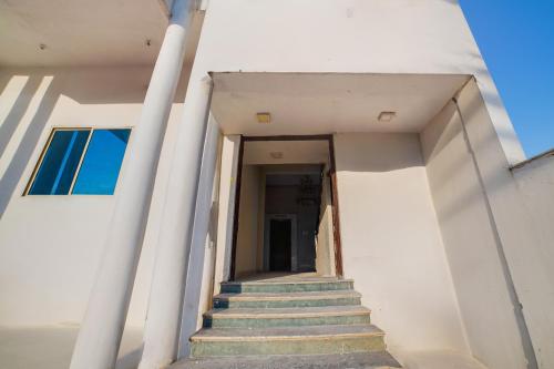 a stairway leading up to a white building with stairs at Hotel O Chouksey Farmstead in Bhopal