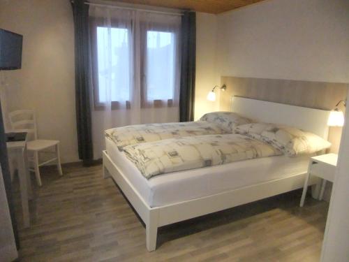 a bedroom with a large white bed with a window at Hotel Weisshorn in Ritzingen