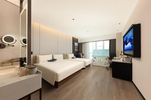 a hotel room with a bed and a flat screen tv at Atour Hotel Chengyang Road Xiangcheng District Suzhou in Suzhou