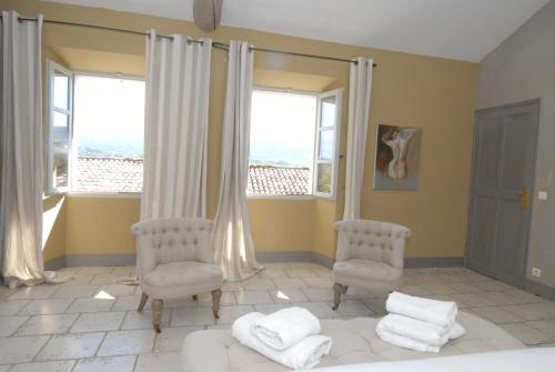 a bedroom with two chairs and a bed and windows at Clos De La Fontaine in Cabrières-dʼAvignon