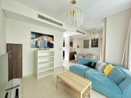 Una sala de estar con un sofá azul y una mesa. en 3 BR Fully Furnished with BBQ Griller, en Dubái