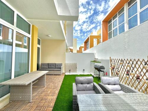 Un patio de un edificio con un banco y césped. en 3 BR Fully Furnished with BBQ Griller, en Dubái