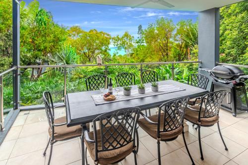 a table and chairs on a balcony with a grill at Pinnacle Apartments on Hamilton Island by HIHA in Hamilton Island