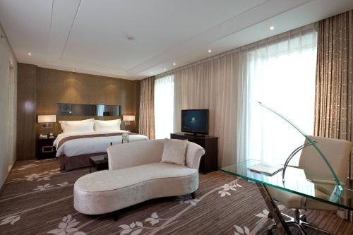 a hotel room with a bed and a couch and a television at The Jade Boutique Hotel in Wuhan