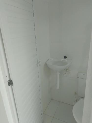 a white bathroom with a sink and a toilet at Apto tipo Studio de temporada no litoral Piauí in Parnaíba