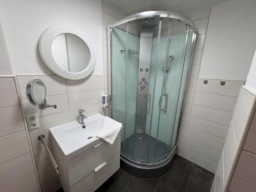 a bathroom with a glass shower and a sink at Hotel-Fritz in Valwig
