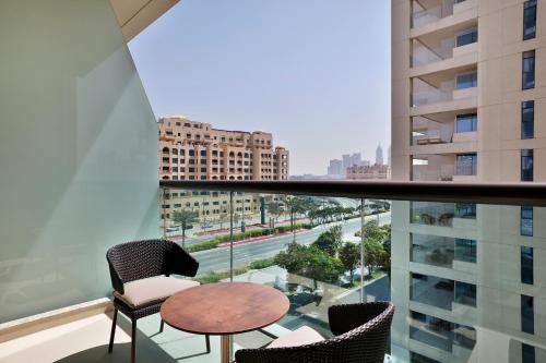 a balcony with chairs and a table and a view of a city at Hilton Dubai Palm Jumeirah in Dubai