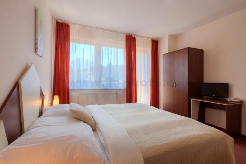 a bedroom with a bed and a window with red curtains at Holiday Park Orava - Hotel Orava in Dolný Kubín