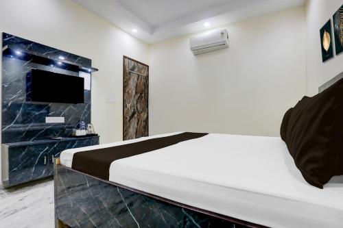 Un dormitorio con una cama blanca y un televisor. en Hotel O Apna Hotel, en Nueva Delhi