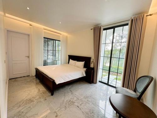 a bedroom with a bed and a large window at Biệt Thự chủ nhà tự doanh tại FLAMINGOS ĐẠI LẢI RESORT in Phúc Yên