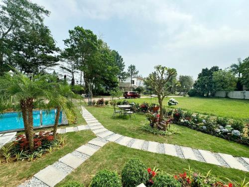 a garden with a pool and a picnic table at Biệt Thự chủ nhà tự doanh tại FLAMINGOS ĐẠI LẢI RESORT in Phúc Yên