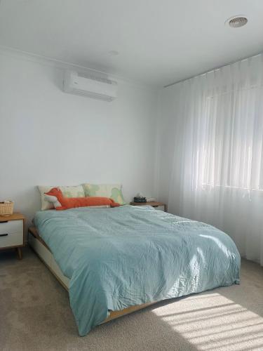 a bedroom with a bed with a blue comforter at Central Nest at Caroline Springs in Caroline Springs