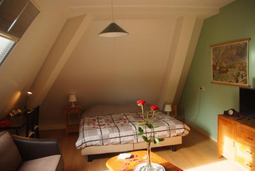 a bedroom with a bed and a table with flowers on it at B&B Noflik Haule in Haule
