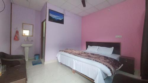 a bedroom with a bed with a pink wall at Kafal Tree Cottage in Phata
