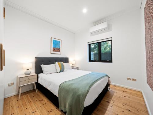 a white bedroom with a bed and a window at The Mitchell Bondi in Sydney