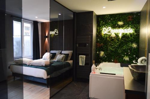 a bedroom with a bed and a bathroom with a sink at L'Escapade - Love room & spa in Haguenau