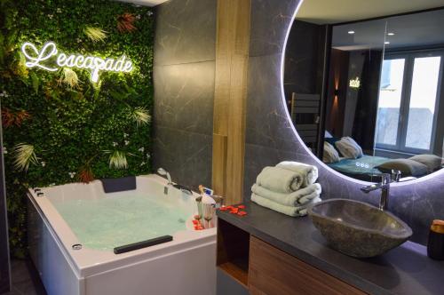 a bathroom with a tub and a sink and a mirror at L'Escapade - Love room & spa in Haguenau