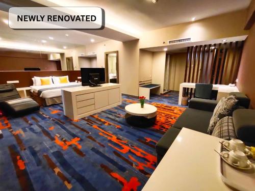 a room with a hotel room with a bed and a tv at Hotel Capital Kota Kinabalu in Kota Kinabalu